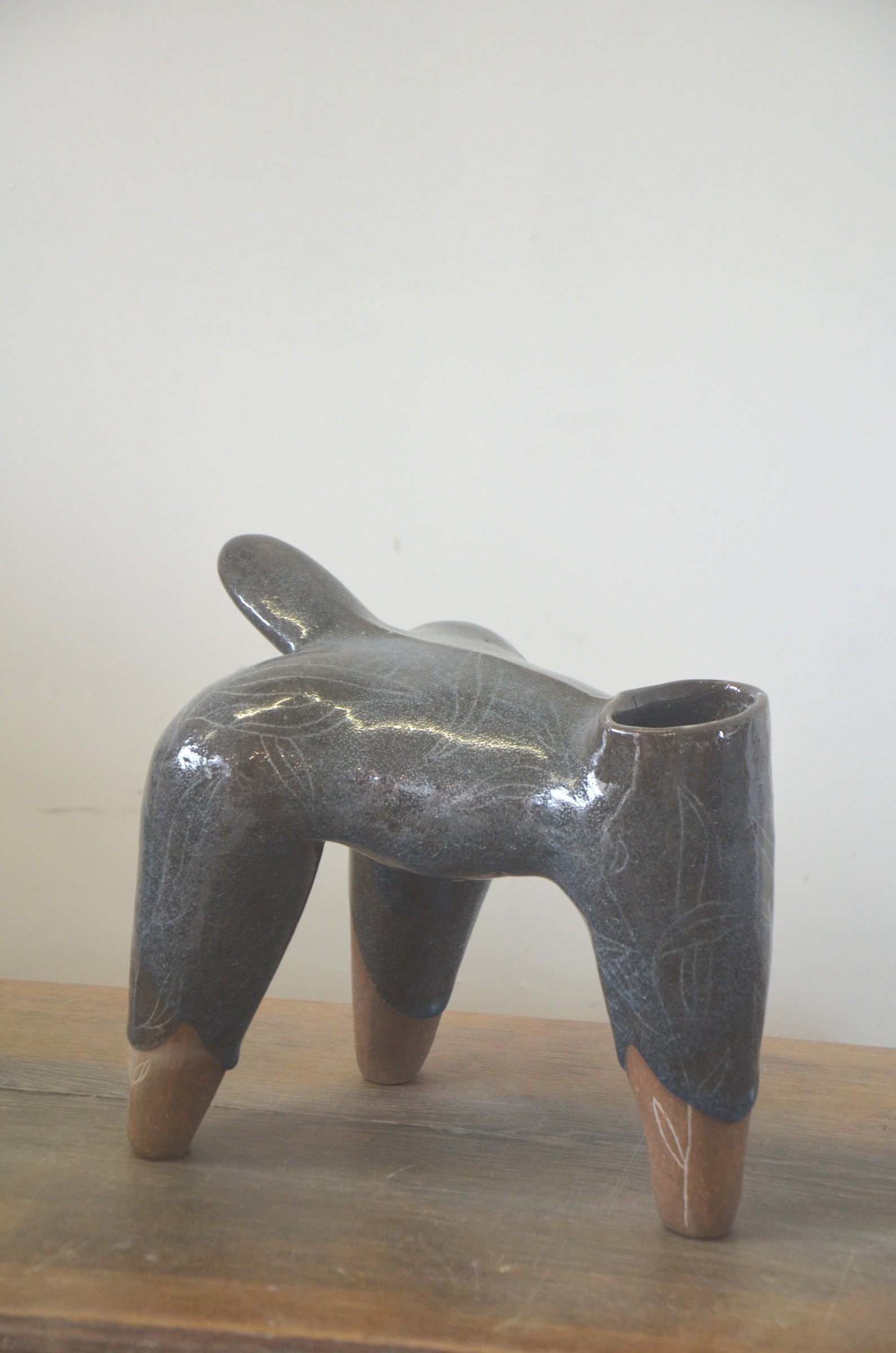 Pièce à quatre pieds couverte d'un émail gris brillant, les pieds en terre nue.
