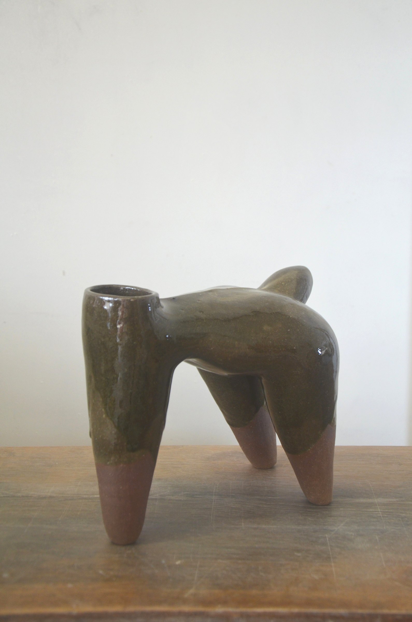 Pièce à quatre pieds couverte d'un émail vert-brun coulant, les pieds en terre nue.