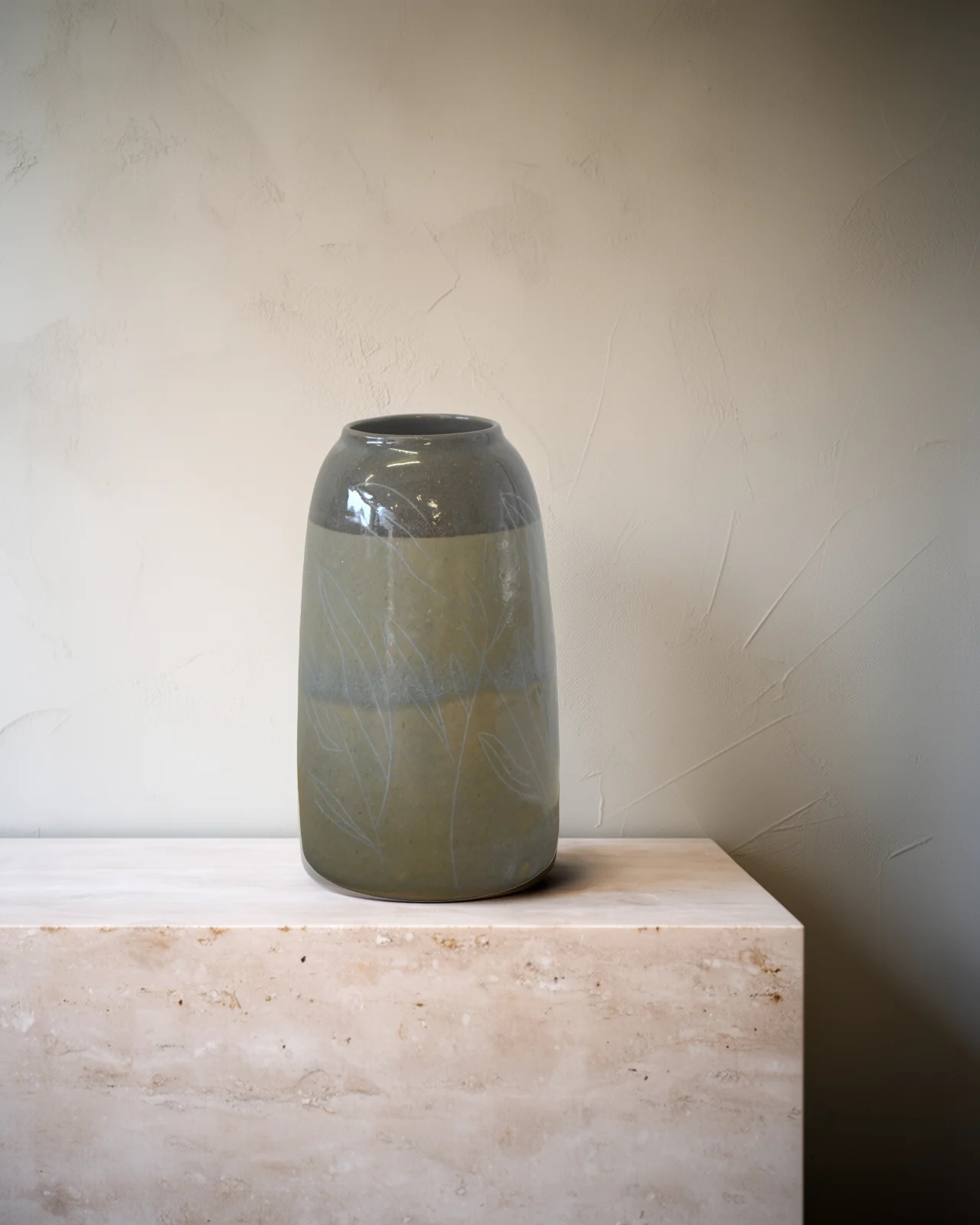 Vase en grès à col gris brillant, gravé de feuillages, sur un socle de travertin pâle.
